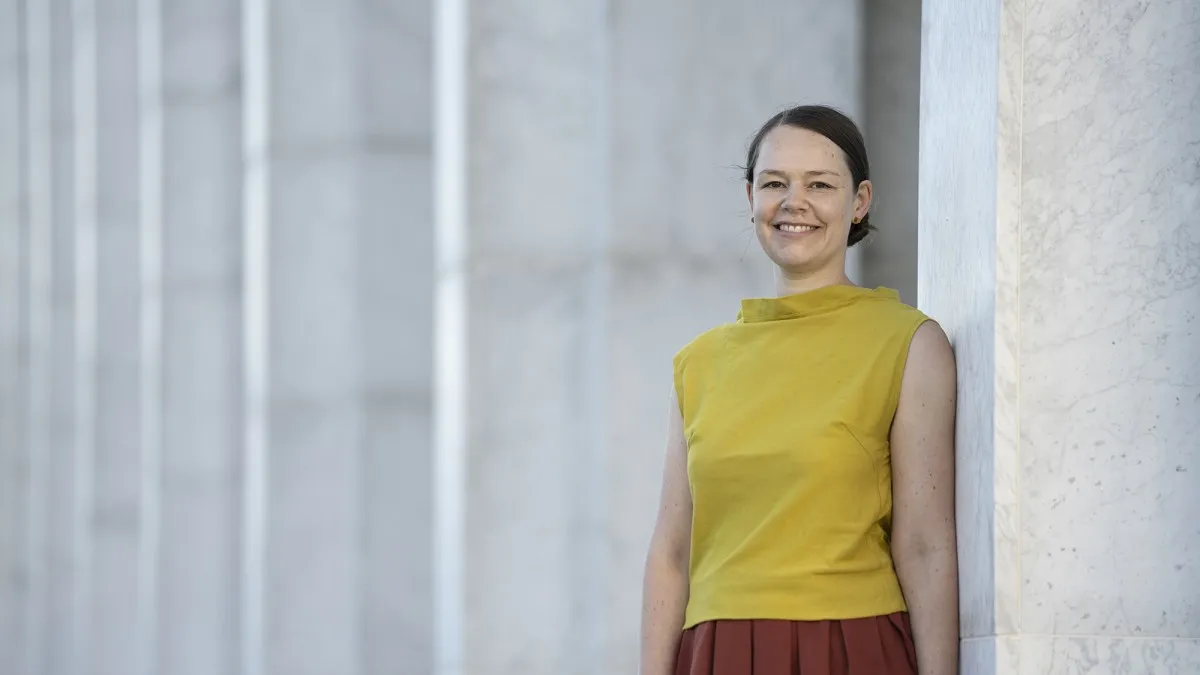 A woman in mustard top smiling at the camera