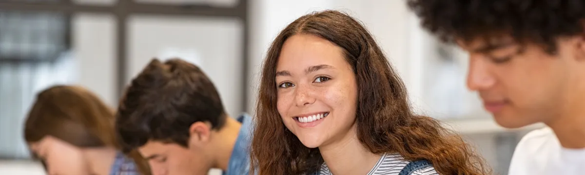 Portrait of happy high school girl studying in class