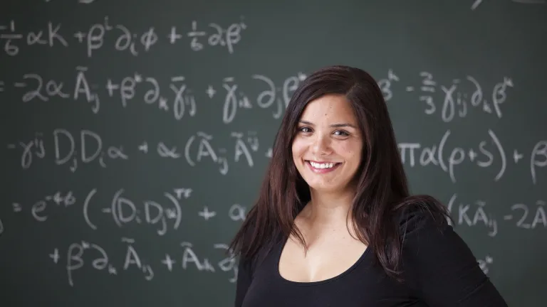 A woman standing in front of a black board